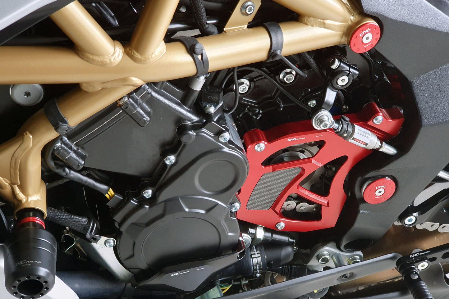 Rode CNC Racing tandwielcover gemonteerd op MV Agusta – aluminium CNC-onderdeel met zichtbaar carbon paneel, racing quickshifter setup en zwarte CNC Racing accessoires rondom