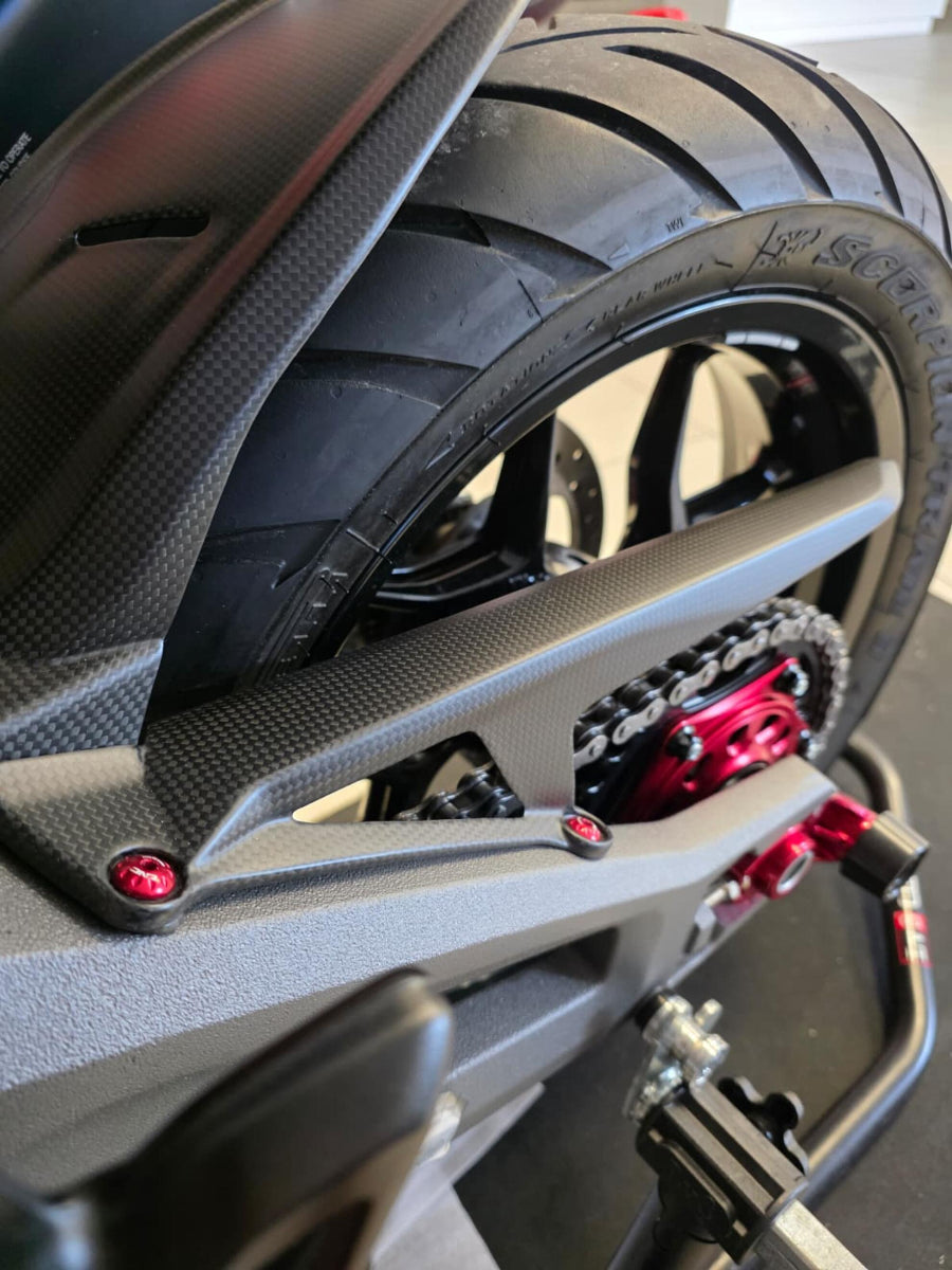 Carbon kettingbeschermer op de achterbrug van de Ducati Multistrada V2, met zicht op ketting, tandwiel en achterwiel.